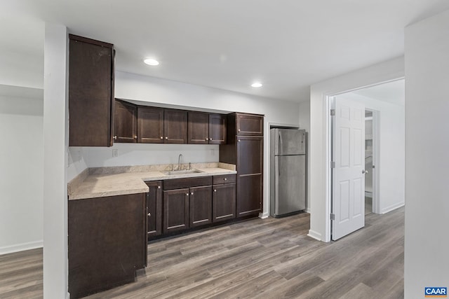 kitchen featuring sink, stainless steel refrigerator, hardwood / wood-style flooring, and dark brown cabinetry