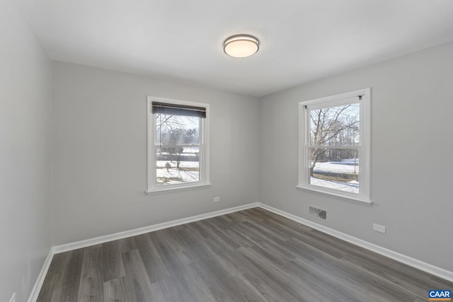 empty room with dark wood-type flooring and a healthy amount of sunlight