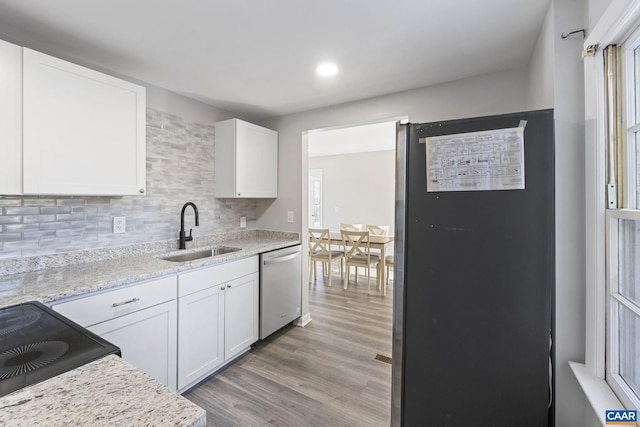 kitchen with white cabinetry, stainless steel dishwasher, light hardwood / wood-style flooring, and sink