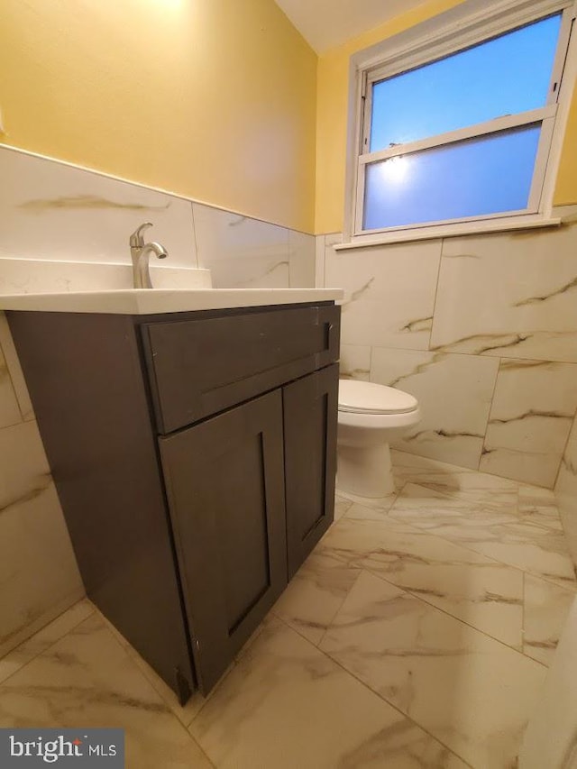 bathroom with toilet, tile walls, and vanity