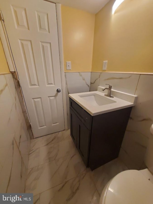 bathroom featuring tile walls, toilet, and vanity