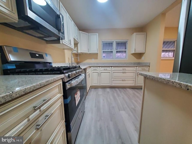 kitchen featuring light stone countertops, appliances with stainless steel finishes, and light hardwood / wood-style flooring