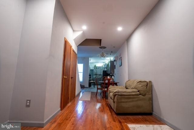 corridor featuring hardwood / wood-style flooring and a notable chandelier