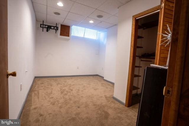 basement with a drop ceiling and light carpet