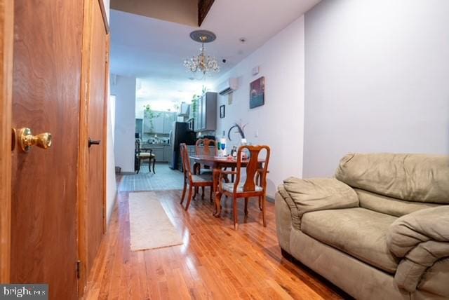 dining area with light wood-type flooring, an AC wall unit, and a chandelier