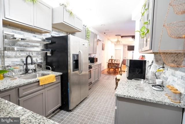 kitchen with light tile patterned floors, stainless steel appliances, gray cabinetry, tasteful backsplash, and sink