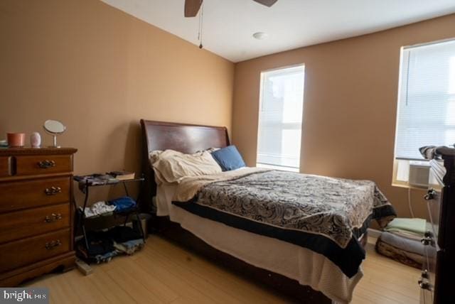 bedroom with ceiling fan, cooling unit, multiple windows, and light hardwood / wood-style floors