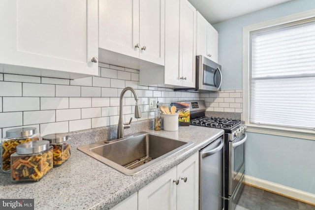 kitchen featuring appliances with stainless steel finishes, white cabinetry, tile patterned floors, tasteful backsplash, and sink