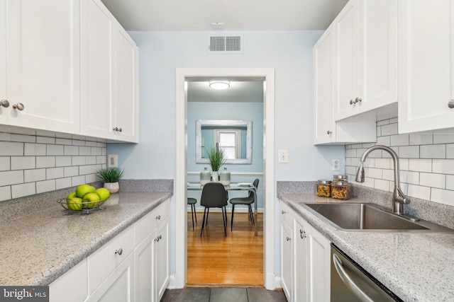 kitchen with light stone countertops, sink, dark tile patterned flooring, and white cabinets