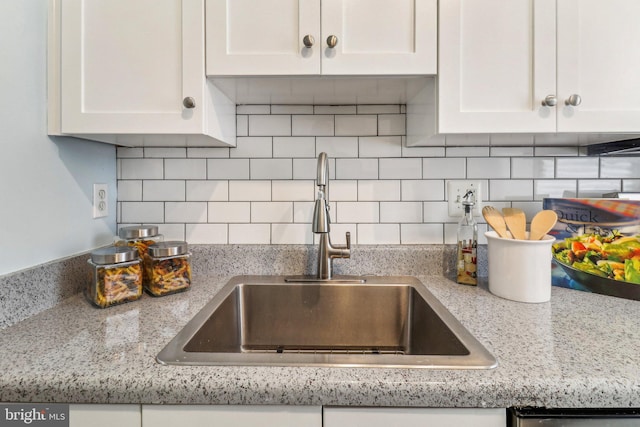 kitchen featuring white cabinets, decorative backsplash, and sink