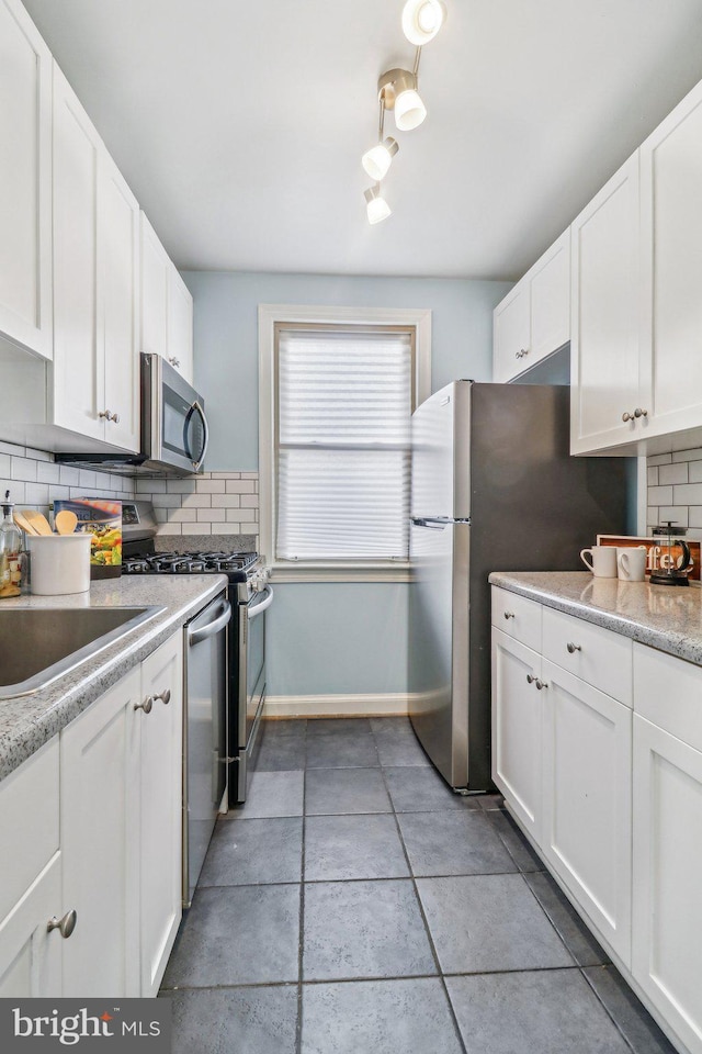 kitchen featuring white cabinets, backsplash, appliances with stainless steel finishes, and sink