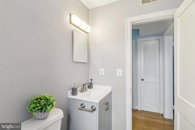 bathroom featuring toilet, wood-type flooring, and vanity