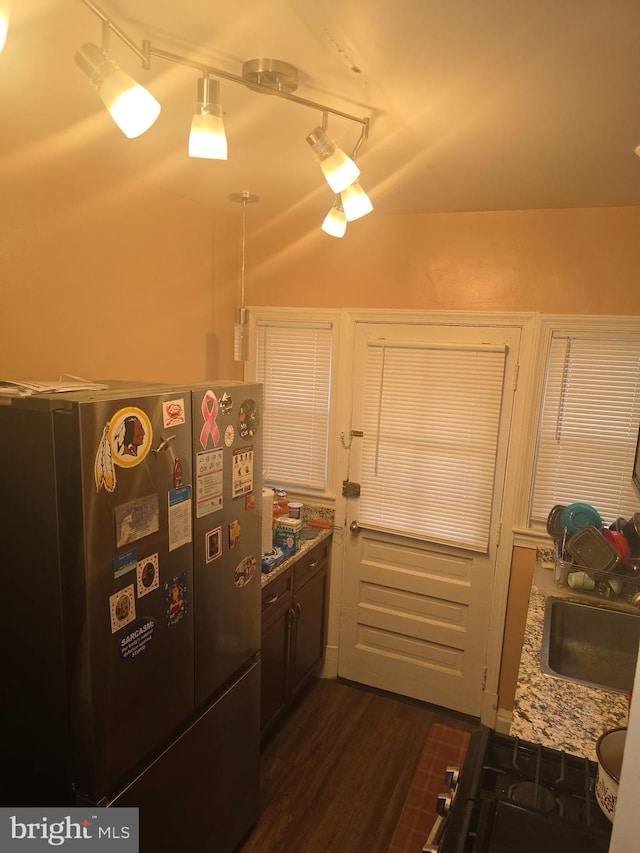 kitchen with light stone countertops, black refrigerator, and dark hardwood / wood-style floors