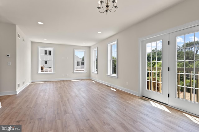 unfurnished living room featuring light hardwood / wood-style floors and a notable chandelier