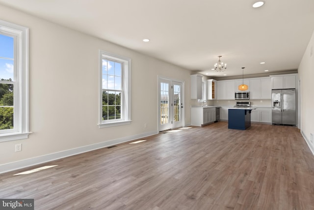 kitchen with appliances with stainless steel finishes, plenty of natural light, a kitchen island, and pendant lighting