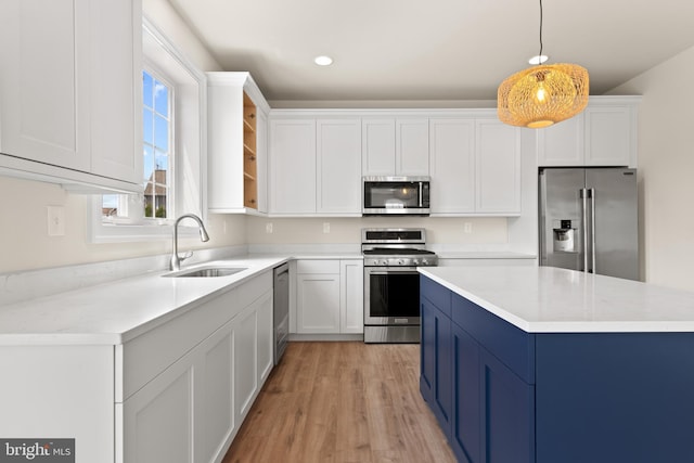 kitchen with white cabinetry, appliances with stainless steel finishes, pendant lighting, light hardwood / wood-style flooring, and sink