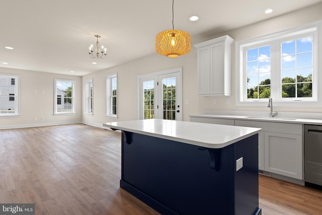 kitchen featuring a center island, pendant lighting, sink, white cabinetry, and a breakfast bar area