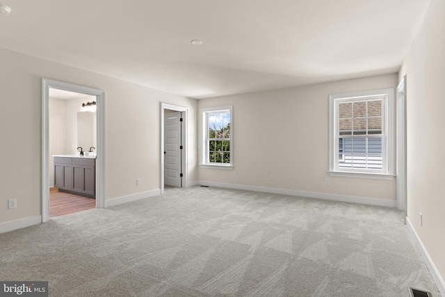 unfurnished bedroom with light colored carpet and ensuite bath