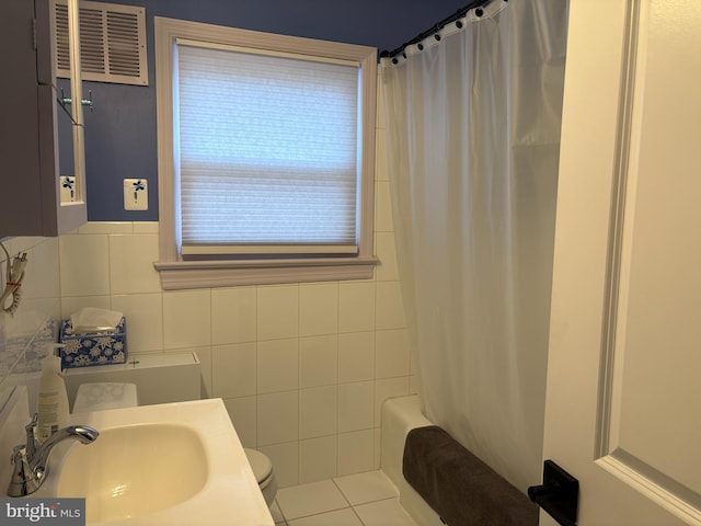 bathroom featuring toilet, tile patterned flooring, tile walls, backsplash, and sink