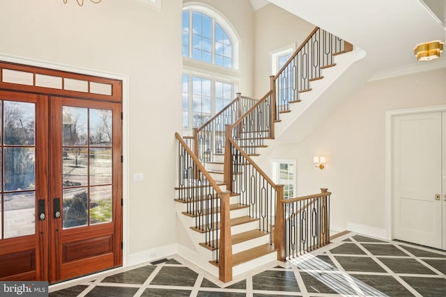 foyer entrance with dark tile patterned floors, crown molding, french doors, and a healthy amount of sunlight