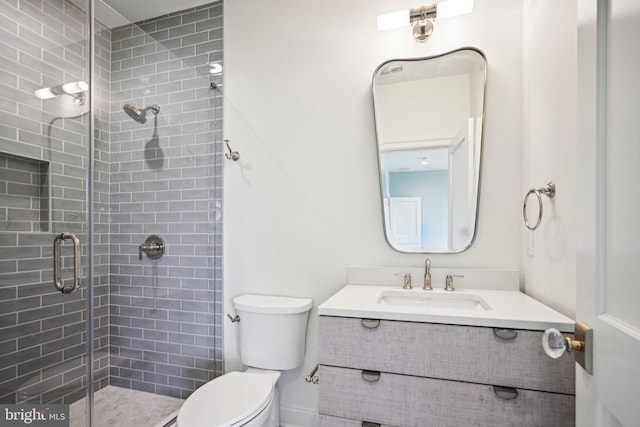 bathroom with toilet, vanity, and a shower with door