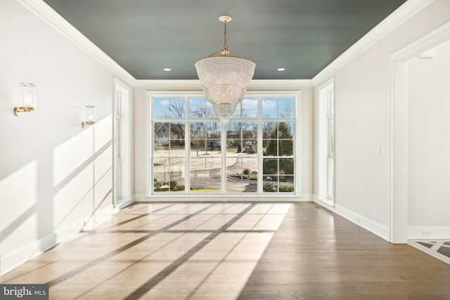 unfurnished dining area with wood-type flooring, crown molding, and a chandelier