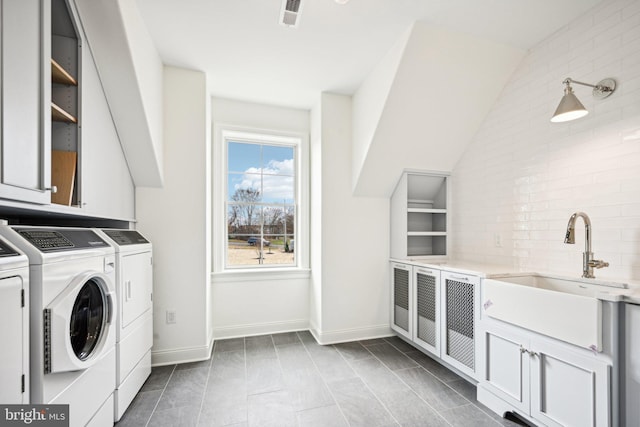 laundry area with cabinets, separate washer and dryer, and sink