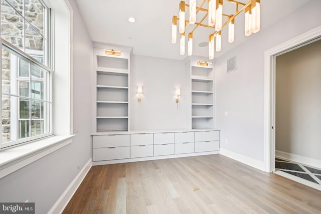 unfurnished bedroom with an inviting chandelier and light hardwood / wood-style floors