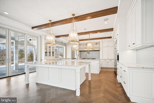 kitchen featuring a large island, white cabinetry, dark parquet flooring, and beam ceiling