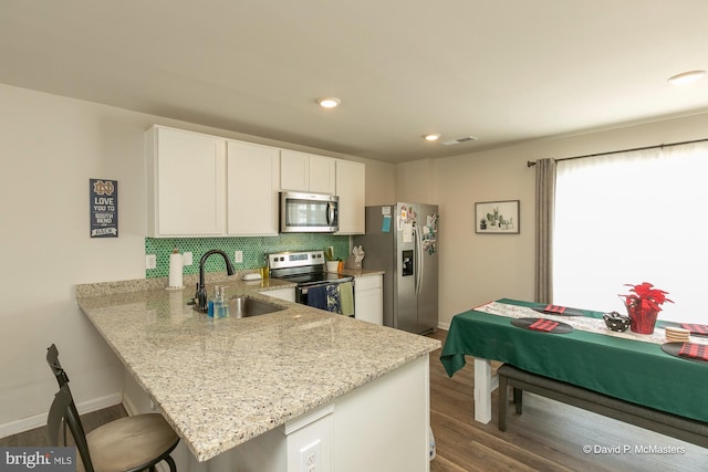 kitchen with sink, white cabinetry, kitchen peninsula, and appliances with stainless steel finishes