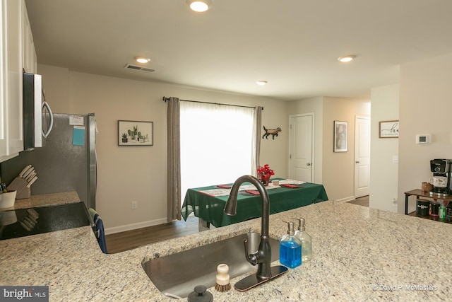 kitchen featuring light stone countertops, sink, and range