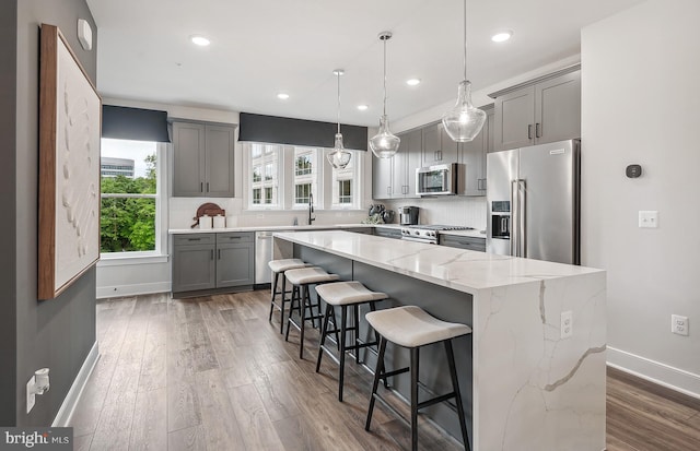 kitchen with a large island, gray cabinets, a breakfast bar area, premium appliances, and decorative backsplash