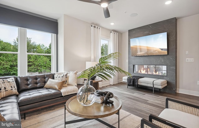 living room with hardwood / wood-style floors, a tile fireplace, and ceiling fan