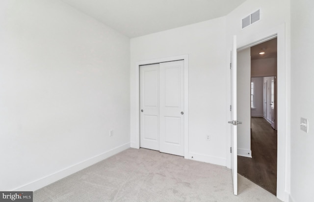 unfurnished bedroom featuring light colored carpet and a closet