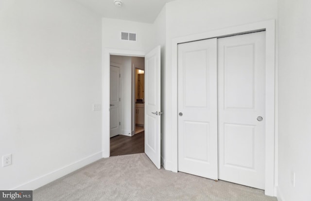 unfurnished bedroom with a closet and light carpet