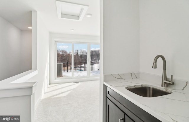 interior space with carpet floors, light stone countertops, and sink