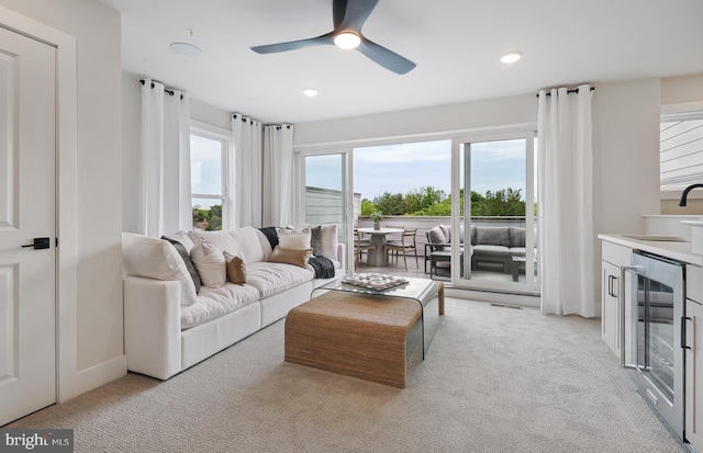 carpeted living room featuring sink, wine cooler, and ceiling fan