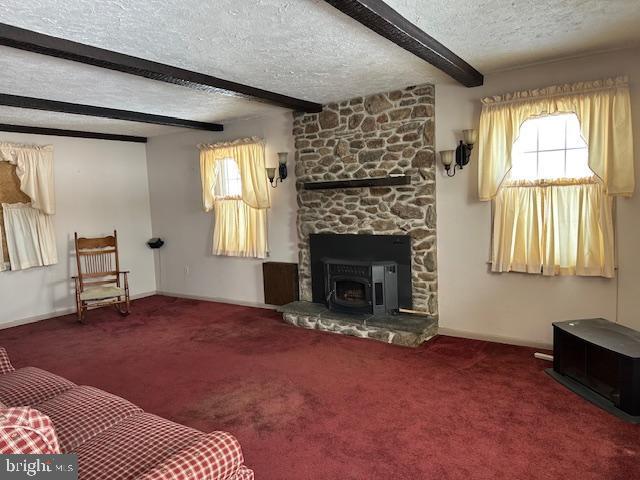 living room with carpet flooring, plenty of natural light, beam ceiling, and a textured ceiling