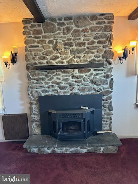 details featuring a textured ceiling, a wood stove, beamed ceiling, and carpet flooring