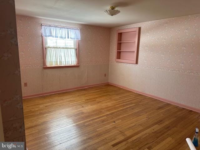 empty room with built in features and light hardwood / wood-style flooring