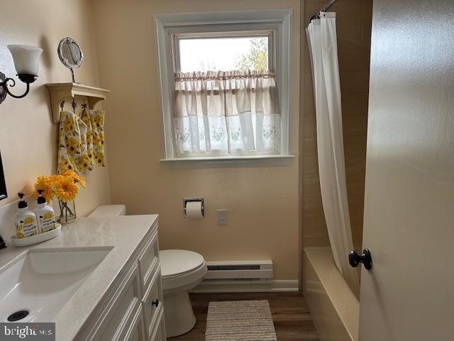 full bathroom with hardwood / wood-style floors, vanity, a baseboard heating unit, toilet, and shower / bath combo