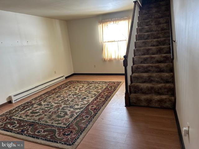 spare room featuring wood-type flooring and a baseboard heating unit