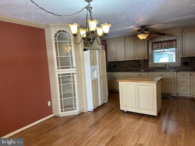 kitchen featuring cream cabinets, paneled built in fridge, light wood-type flooring, and decorative light fixtures