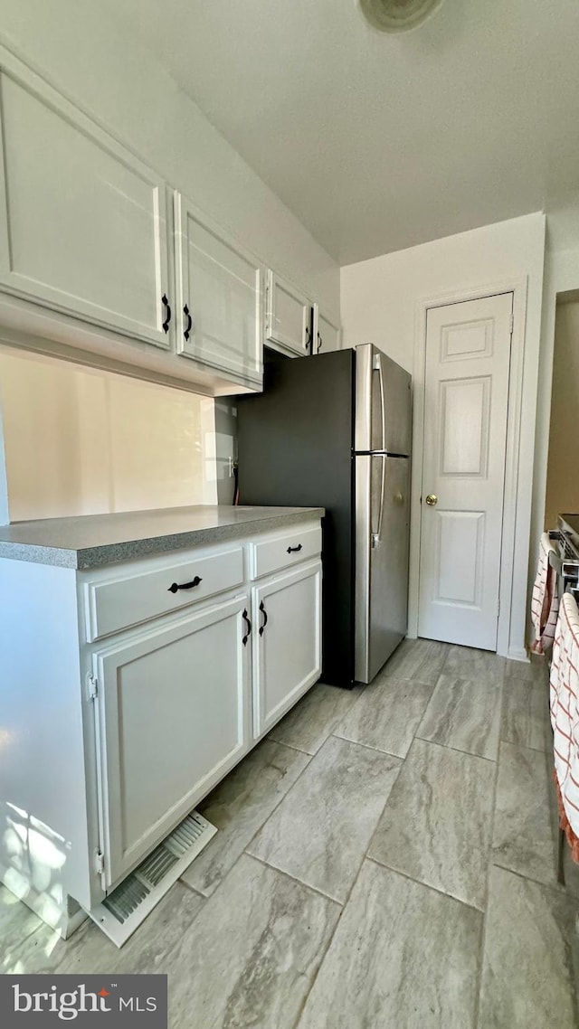 kitchen with white cabinets and stainless steel fridge