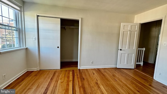 unfurnished bedroom with multiple windows, a closet, and light hardwood / wood-style flooring