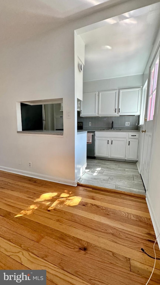 kitchen featuring white cabinets, dishwasher, tasteful backsplash, light hardwood / wood-style floors, and sink