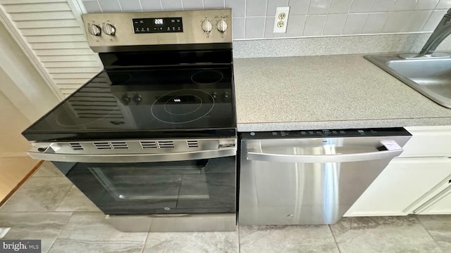 kitchen featuring stainless steel dishwasher, light tile patterned floors, and sink