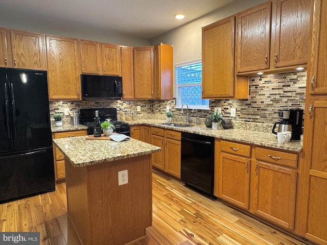 kitchen with sink, light stone counters, tasteful backsplash, and black appliances