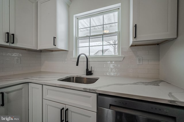 kitchen with backsplash, dishwasher, sink, white cabinetry, and light stone counters