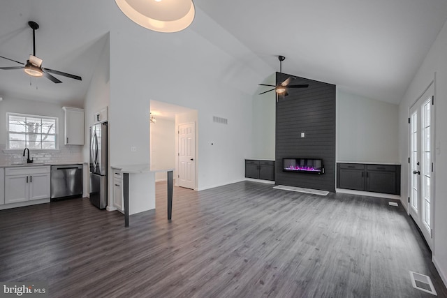 unfurnished living room with dark wood-type flooring, a fireplace, plenty of natural light, and high vaulted ceiling